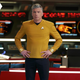 Anson Mount's Captain Christopher Pike stands hands on hips at the front of the USS Enterprise's bridge, as officers work at stations in the background behind him.
